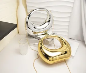 Detail view of circular hollow metal chain bags in polished gold and silver finishes