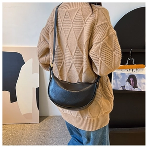 Detailansicht einer schwarzen Halbmond-Tasche aus Kunstleder getragen von einem Modell