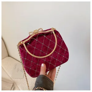 Détail du sac boîte en velours bordeaux avec matelassage diamant et fermoir nœud doré