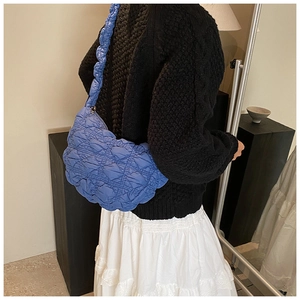 Detail of a vibrant blue quilted cloud shoulder bag with puffy diamond stitching texture