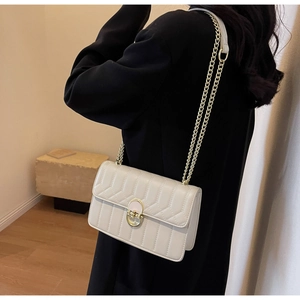 Detailaufnahme der cremeweißen Steppledertasche mit goldener Kette und edler Metallschließe