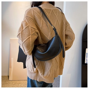 Schwarze Hobo-Tasche mit Kieseltextur, getragen von einem Model im Strickpullover