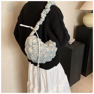 Detail of light blue quilted hobo bag with bubble texture and ruffled shoulder strap