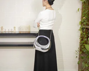 Modern silver irregular acrylic evening bag with a thin gold chain strap shown on model