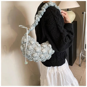 Detail of light blue pleated puffy shoulder bag with textured quilted fabric on model