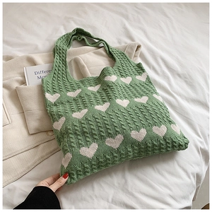 Close-up of green knitted heart tote bag showing chunky knit texture and soft yarn