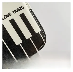 Macro shot of piano keyboard print and LOVE MUSIC text on pebbled leather bag surface