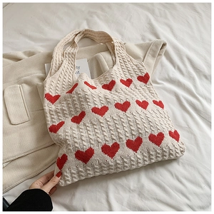Detail of chunky knit texture and red heart jacquard on beige crochet tote bag