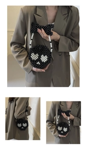Detail of handmade black beaded crossbody bag with white heart pattern and bow handle