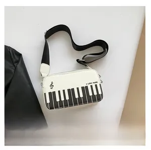 Size comparison of white piano keyboard crossbody bag next to a smartphone device