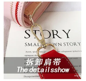Détail du sac rose à côté rayé montrant le crochet doré et la bandoulière en cuir rouge