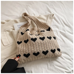 Detailed knit texture of a cream tote bag with black heart patterns and cable stitching