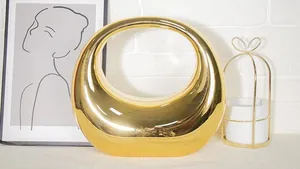 Close-up of minimalist glossy gold round handbag with smooth mirror finish and ring handle