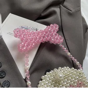 Detail of handmade pearl bead bag with unique pink crystal bow handle on grey blazer