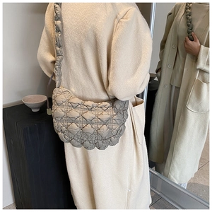 Quilted half-moon shoulder bag in beige shown on model with reflective mirror effect