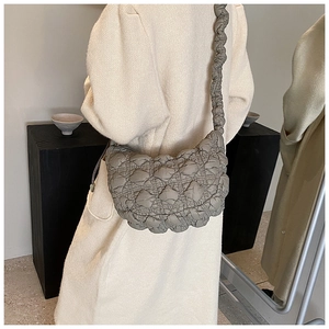 Detail of grey quilted cloud bag worn over the shoulder showing the soft puffed texture