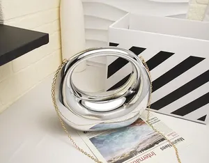 Close-up of a silver donut-shaped metal handbag with chain on a stylish prop background