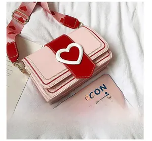 Vue détaillée du sac bandoulière cœur rose avec large sangle imprimée et design multicouche