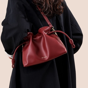 Sac seau bordeaux rétro avec cordon de serrage et détails dorés sur un manteau noir