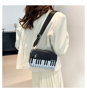 Detail view of piano key crossbody bag featuring musical notes and adjustable strap
