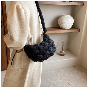 Detail view of a black quilted puffer hobo bag featuring soft texture and a wide strap