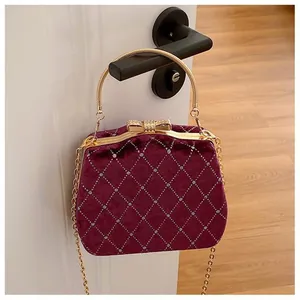 Détail d'un sac de soirée en velours bordeaux avec matelassage et fermoir nœud doré