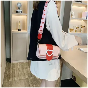 Détail du sac à bandoulière rose et rouge avec large sangle porté par un mannequin femme
