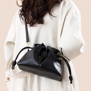 Sac seau nuage noir minimaliste avec cordon porté sur un manteau beige élégant