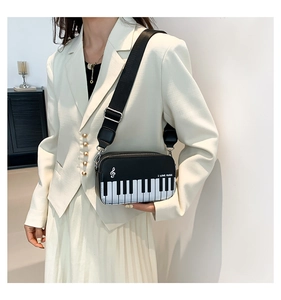Detail of piano key design on crossbody bag featuring I Love Music embroidery and silver hardware