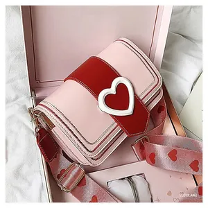 Vue détaillée du sac bandoulière cœur rose et rouge dans un coffret cadeau romantique