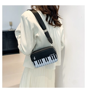Detail of piano keyboard embroidery and I LOVE MUSIC slogan on black crossbody bag