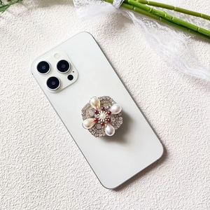 Detailed view of luxury rhinestone floral phone grip with white and burgundy pearls