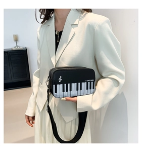 Detail of piano keyboard embroidery and I Love Music slogan on black crossbody bag
