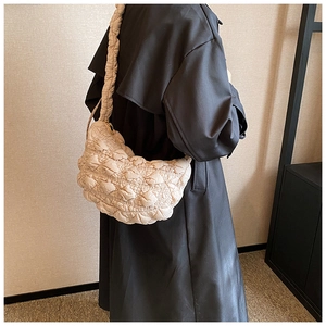 Close-up of beige quilted cloud bag with ruched strap and gold metallic accents