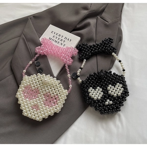 Detail of beaded pearl handbags featuring heart patterns and oversized bow handles