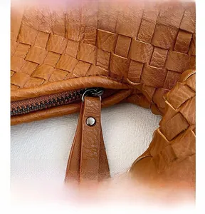 Dettaglio macro della cerniera scorrevole su borsa in pelle intrecciata caramello