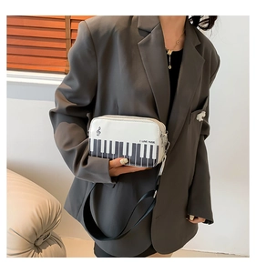 Detail of piano keyboard pattern and I LOVE MUSIC text on white PU leather crossbody bag