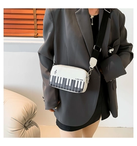 Detail of piano keyboard embroidery on small square crossbody bag with music notes