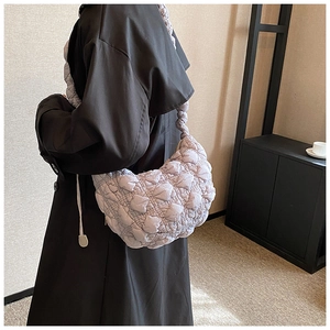 Detail of light purple quilted shoulder bag with puffy textured design on a model