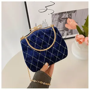 Détail d'une pochette en velours bleu marine avec matelassage diamant et fermoir nœud doré
