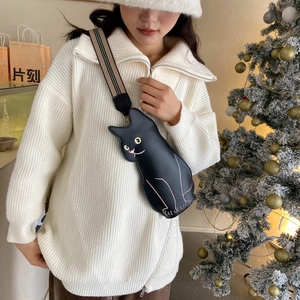 Cute black cat-shaped crossbody bag with striped strap on a female model with a winter vibe