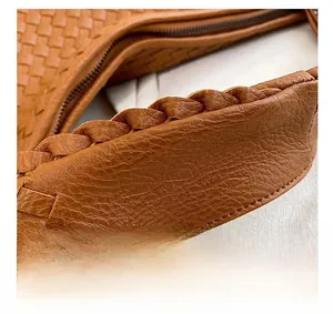 Macro di un manico in pelle intrecciata spessa su una borsa tote marrone intrecciata