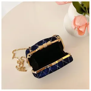 Détail du sac boîte en velours bleu marine avec nœud en strass et chaîne dorée