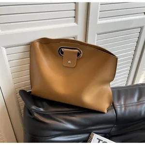 Detail of tan leather clutch with unique hollow metal handle and magnetic snap closure