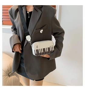 Detail of music-themed crossbody bag with piano key pattern and embroidered strap