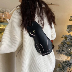 Cute black cat-shaped crossbody bag made of PU leather worn over a white knit sweater
