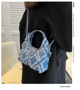 Detail of light blue denim crescent bag with frayed quilted texture and silver buckle