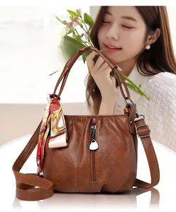 Detail of caramel soft leather handbag with pleated design and silk scarf accessory