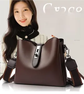 Detail of dark brown leather bucket bag featuring a silver twist lock and wide woven strap