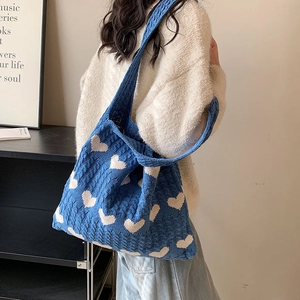Blue knit heart pattern tote bag with wide shoulder strap shown in a lifestyle scene
